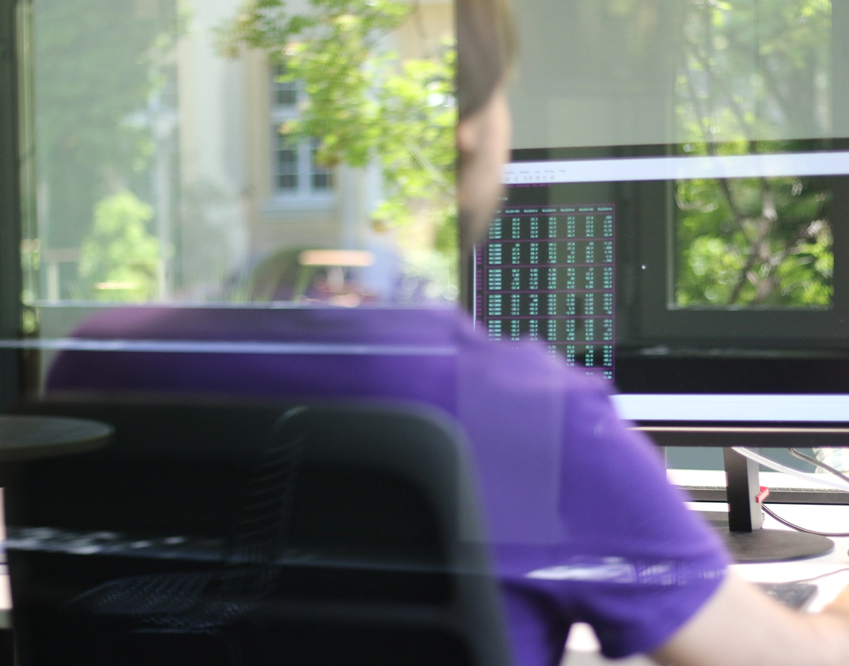  Back view of a man, view on the screen of his computer showing data.